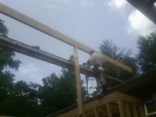 Carpenter setting a ridge beam over a new addition frame — Ice Dam Removal by Roofing Brothers in Niceville
