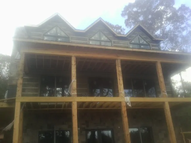 Dormers and porch framing on a large log home under construction — Roof Coating work by our crew in Niceville