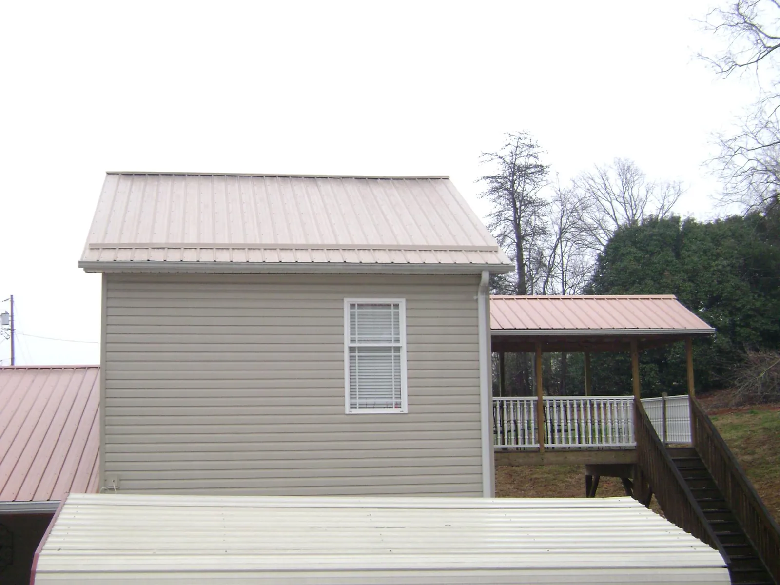 Tan metal roofs on a two story addition and attached porch, from a Roof Replacement job in Niceville